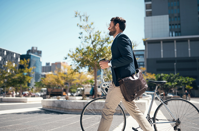 Shot of a young businessman traveling through the city with his bicycle