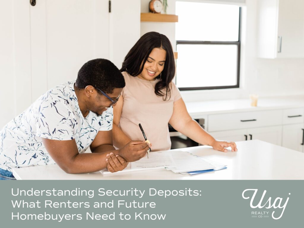 A couple sits at a kitchen counter reviewing paperwork. Below the image white text on a gray-blue background reads, "Understanding Security Deposits: What Renters and Future Homebuyers Need to Know" next to the Usaj Realty logo.