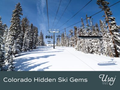 A photo of a ski lift in the Breckenridge ski hill sits above white text on a charcoal background reads, "Colorado Hidden Ski Gems" next to the Usaj Realty logo in white.
