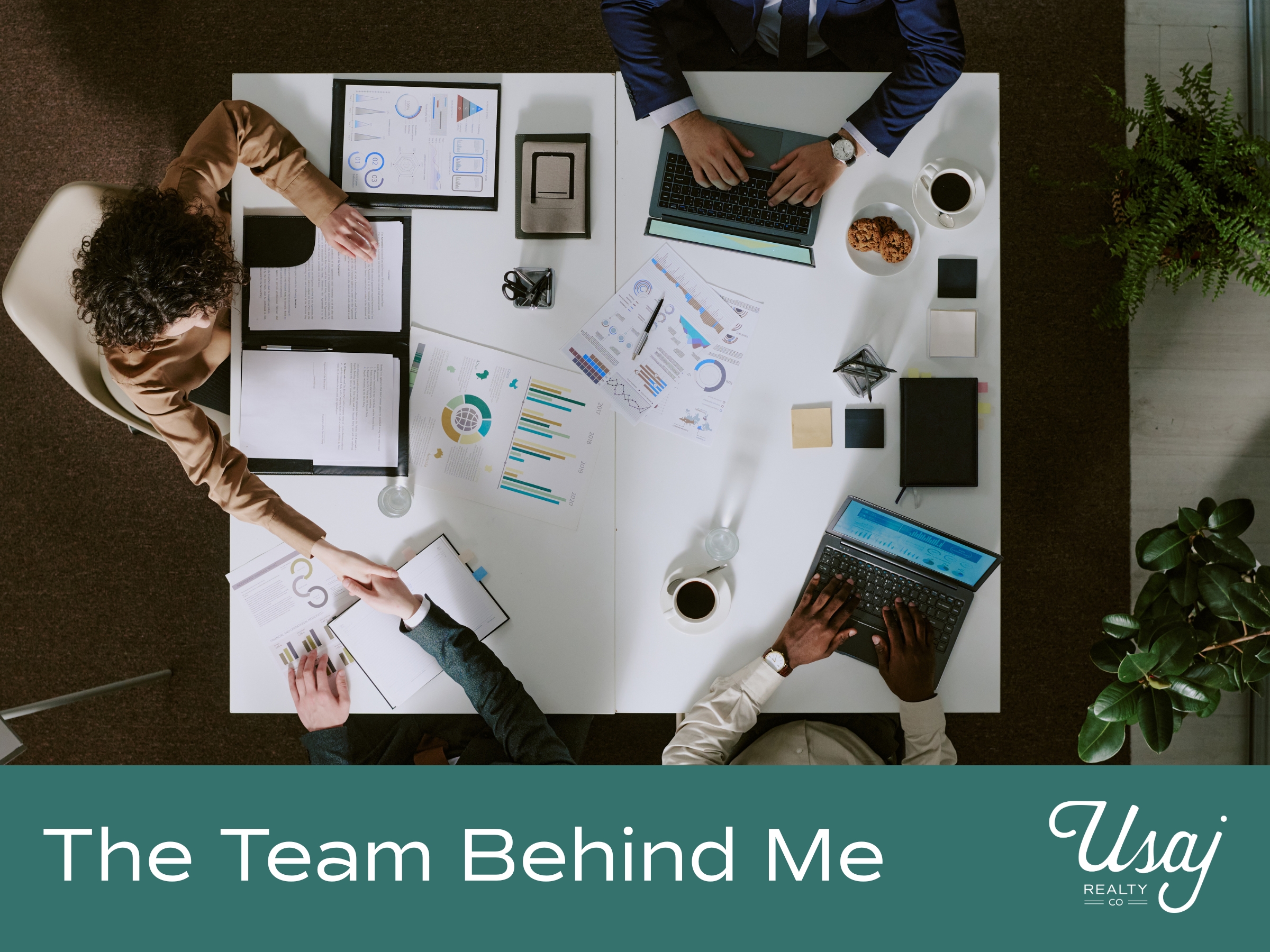 An aerial photo of four coworkers sitting at a table working rests above white text on a teal background that reads, "The Team Behind Me" next to the Usaj Realty logo in white.