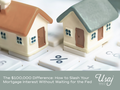 A photo of miniature houses siting on keyboard showing the percentage sign % sits above white text on a gray background that reads, "The $100,000 Difference: How to Slash Your Mortgage Interest Without Waiting for the Fed" next to the Usaj Realty CO logo in white.