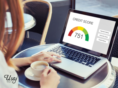 A photo of a red-haired woman looking on her computer which shows a scale for her credit score from red to green.