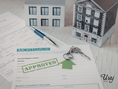 A mortgage preapproval document that is blank sits with house keys and models of homes behind it. In the bottom-right corner the Usaj Realty logo sits.
